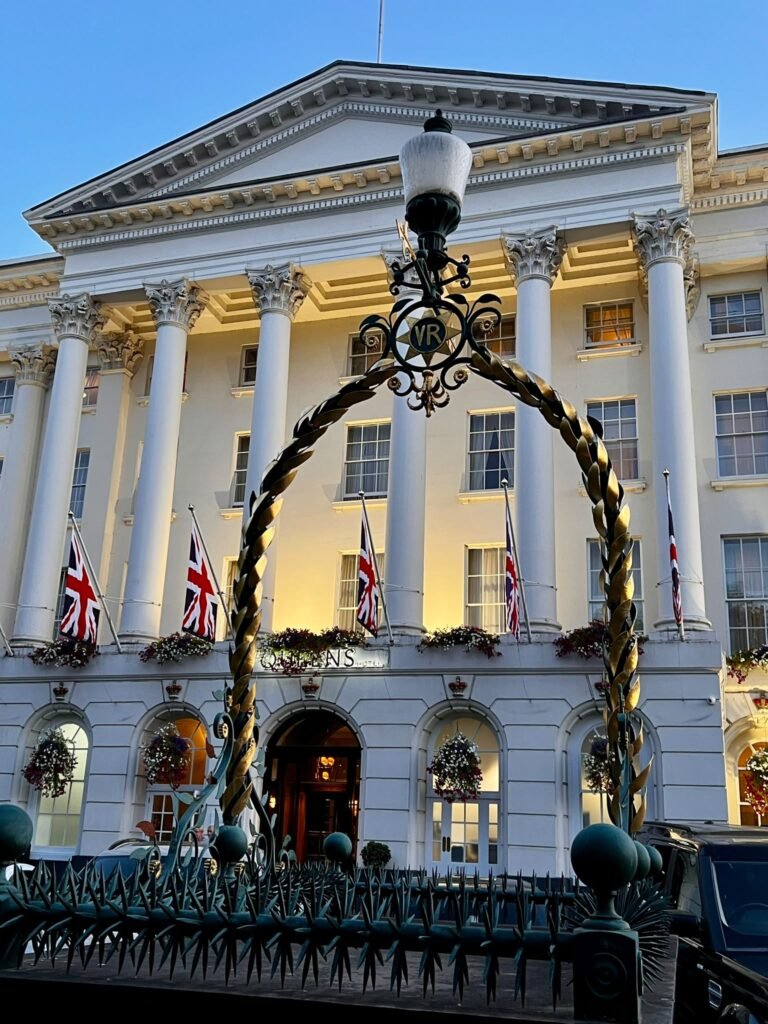 Queens Hotel in Cheltenham illuminated at dusk behind an ornate VR lamp