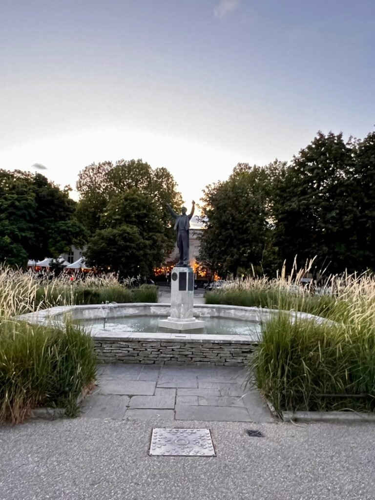 Statue and fountain surrounded by ornamental grasses in Cheltenham at dusk