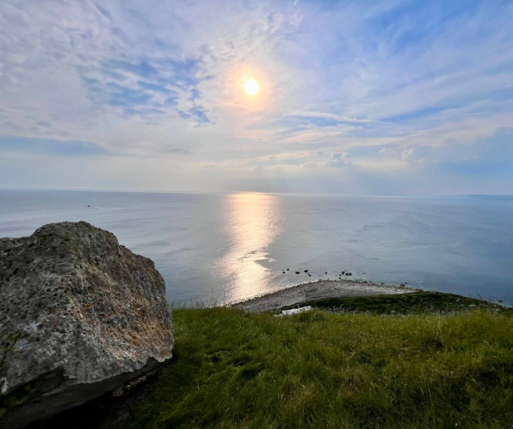 Sunlight reflecting across the sea beside the rocky coast of Portland in Dorset