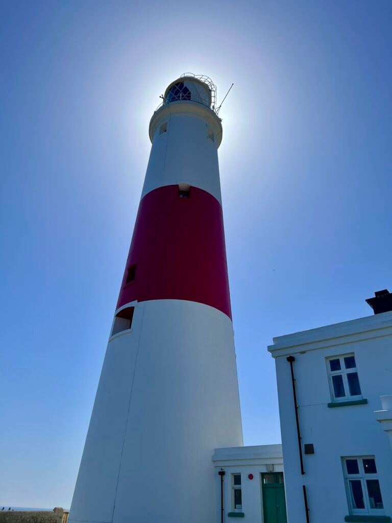 Looking up at the red and white Portland Bill Lighthouse against a blue sky