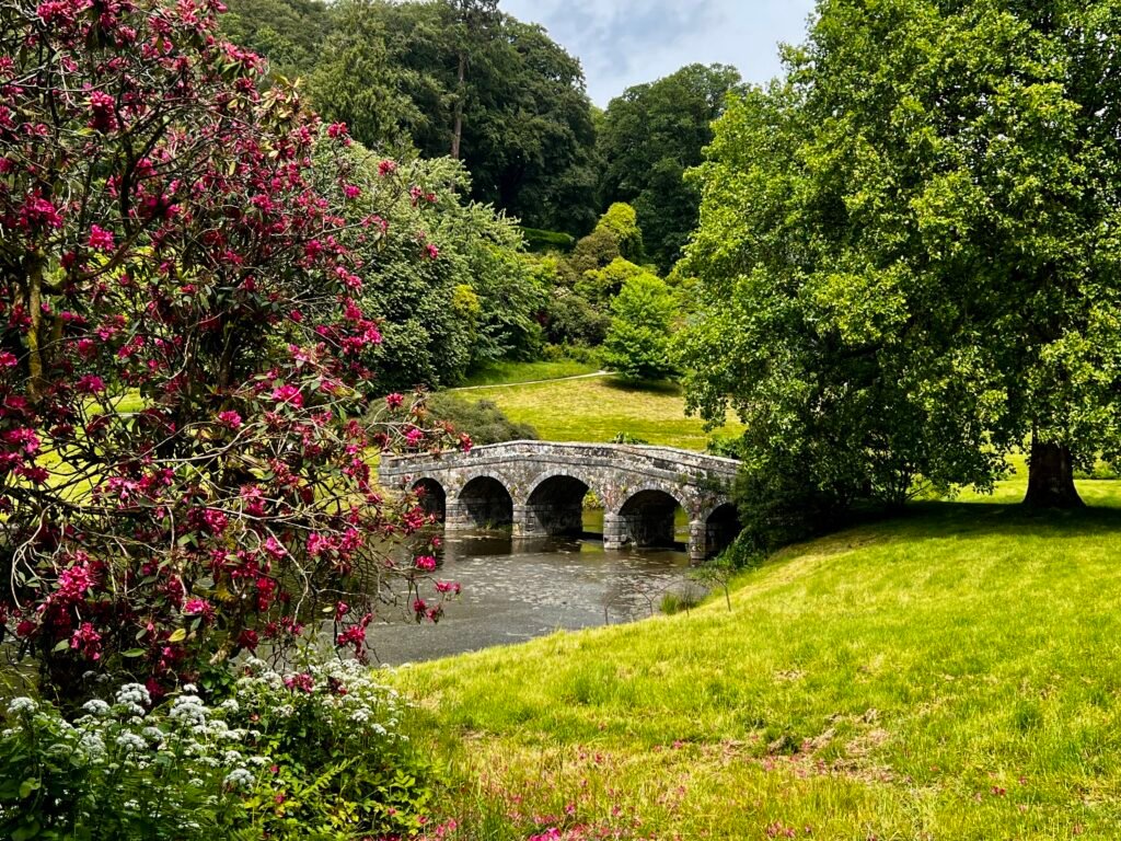 Stone bridge surrounded by flowering plants and landscaped National Trust gardens