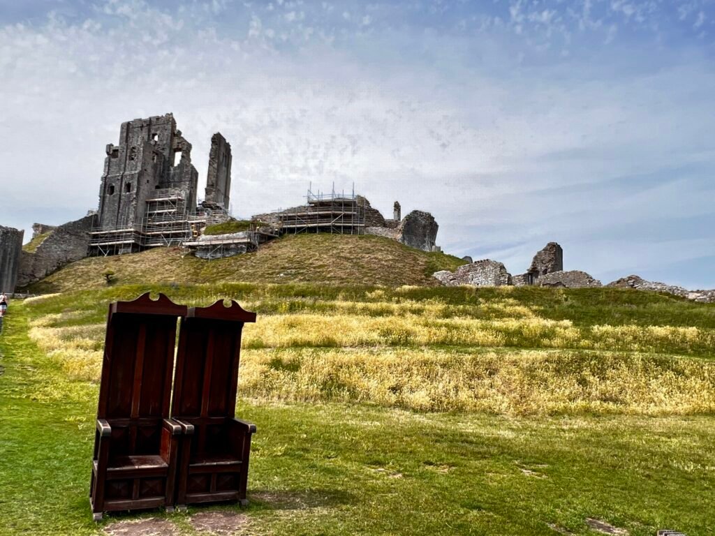 Corfe Castle ruins in Dorset with two wooden chairs in the foreground
