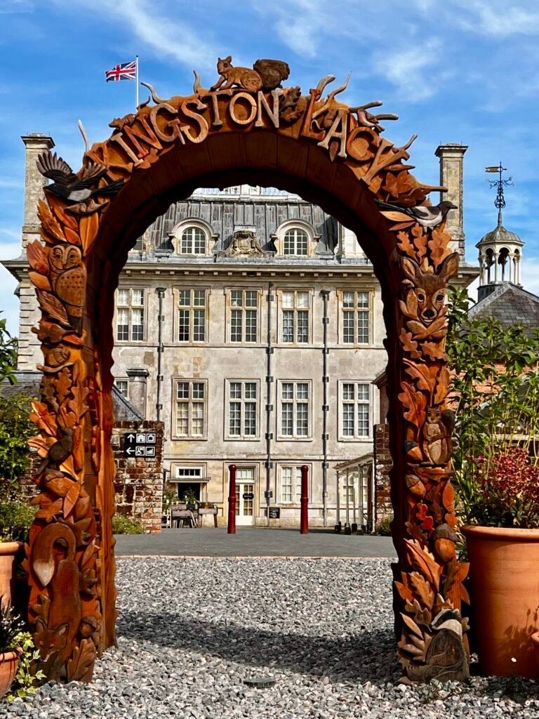 Kingston Lacy house framed by a carved wooden garden arch