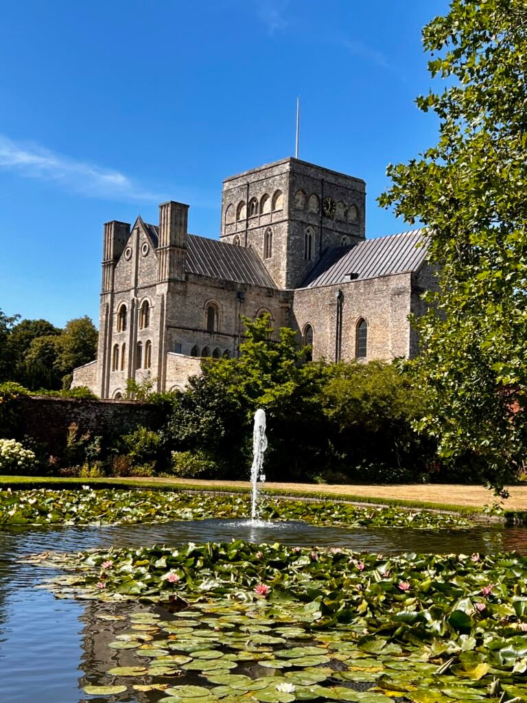 Historic stone building beyond a lily pond and fountain in a National Trust garden