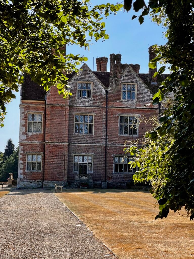Breamore House in Hampshire framed by trees and garden foliage