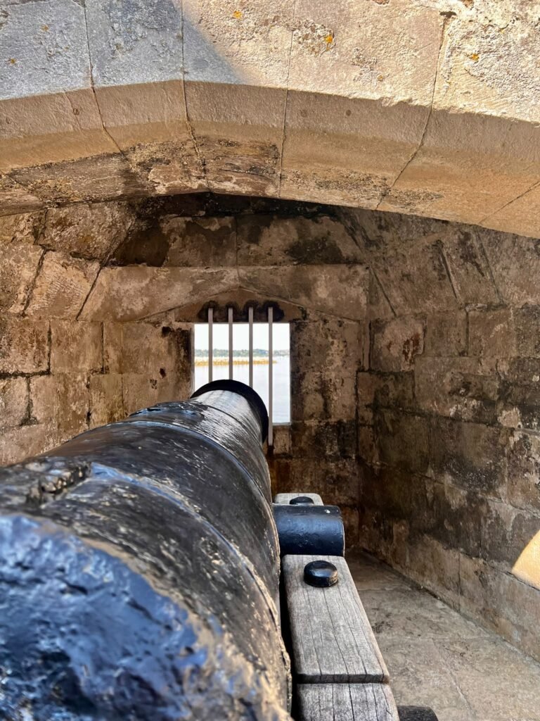 Historic cannon pointing through a barred embrasure at Portland Castle