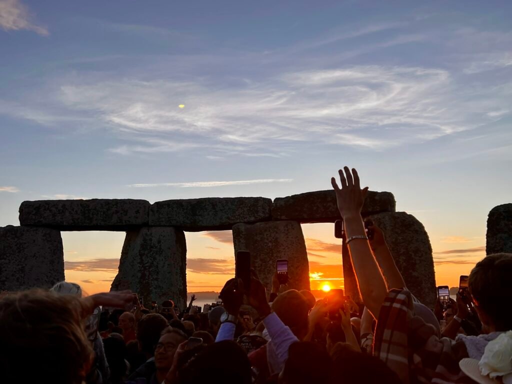 Stonehenge Summer Solstice sunrise appearing between the stones above the waiting crowd.