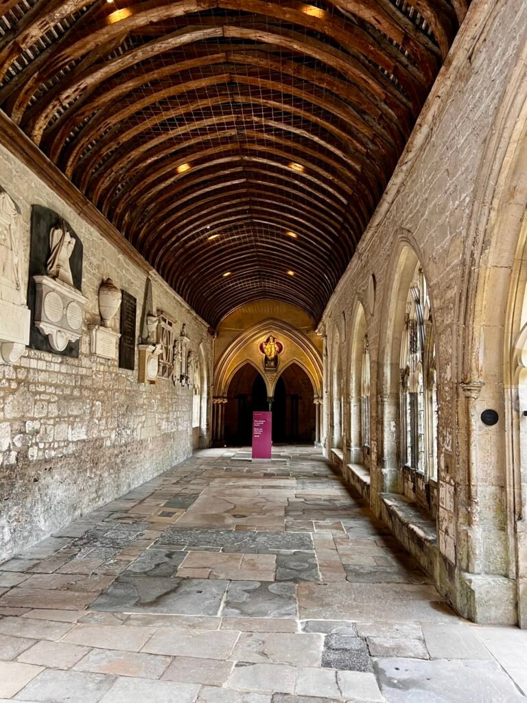 Historic Chichester Cathedral cloister with stone memorials, windows and timber roof