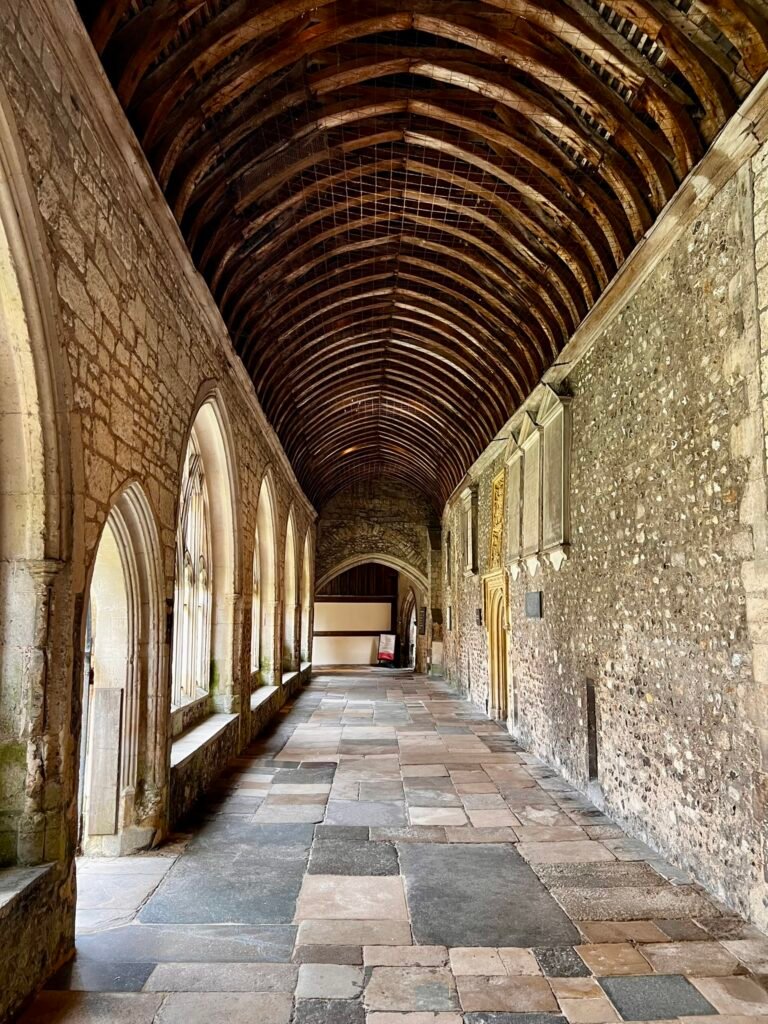 Covered stone passage at Chichester Cathedral with Gothic openings and timber roof