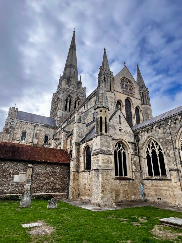 Stone exterior and Gothic windows of Chichester Cathedral beneath its spire
