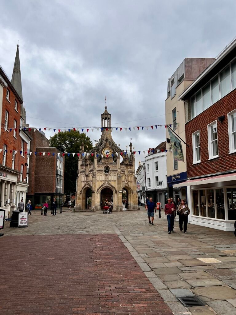 Chichester Cross surrounded by the pedestrianised streets and everyday activity of Chichester city centre, West Sussex.