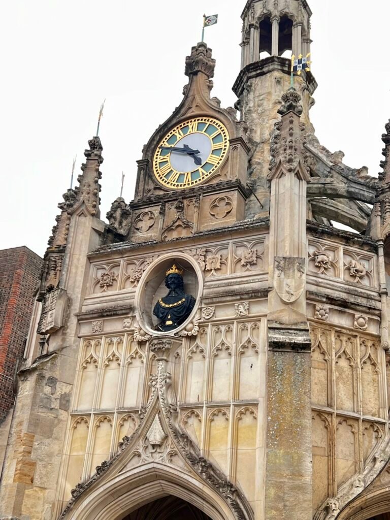 Clock, crowned figure and ornate Gothic stonework on Chichester Cross
