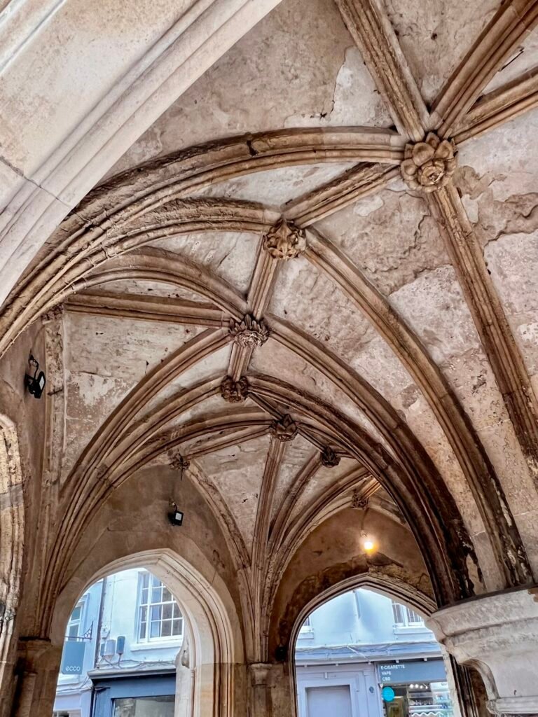 Ribbed stone vaulted ceiling and carved bosses underneath Chichester Cross