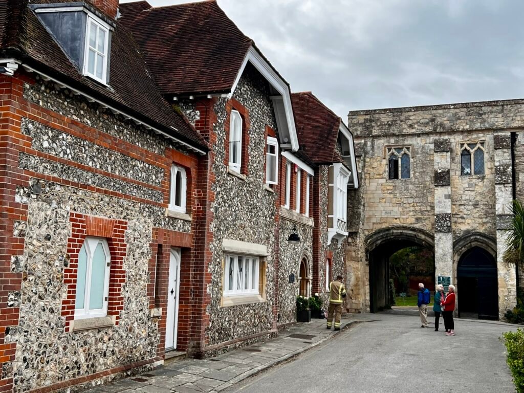 Historic flint and red-brick buildings beside a stone arched gateway in Chichester