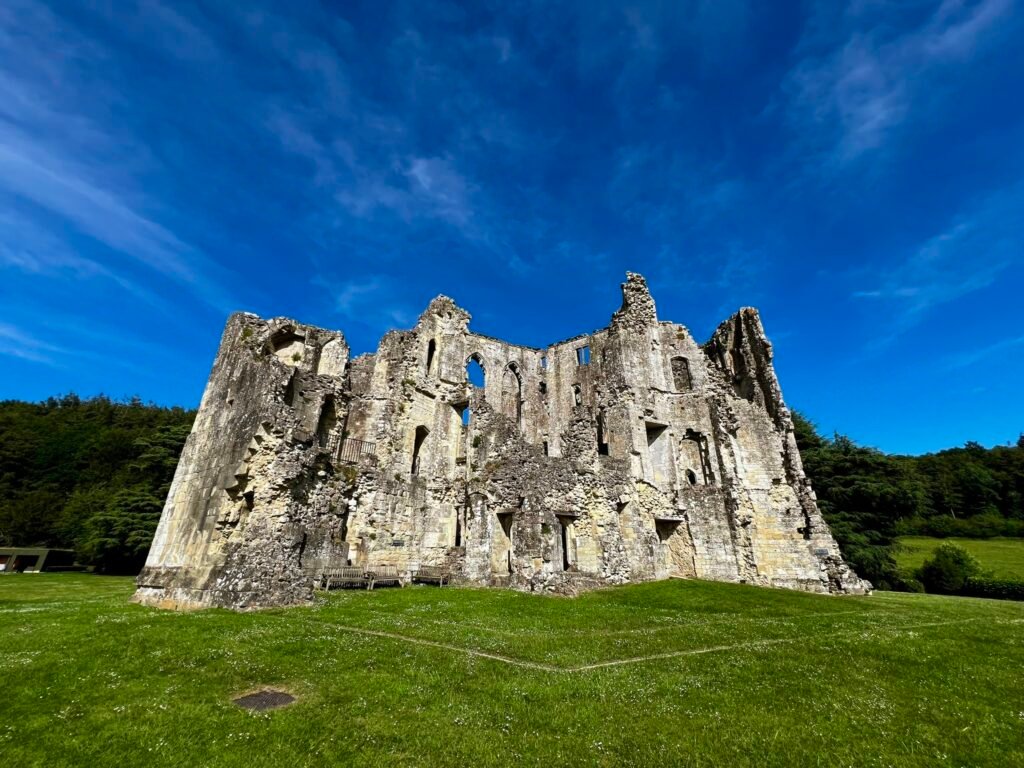 Heavily ruined exterior wall of Old Wardour Castle beneath a deep blue sky