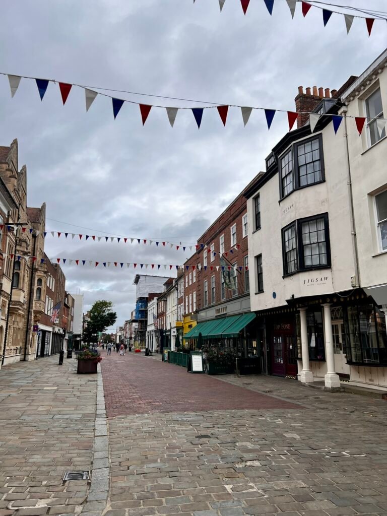 Quiet pedestrianised street in Chichester city centre with bunting and historic shopfronts