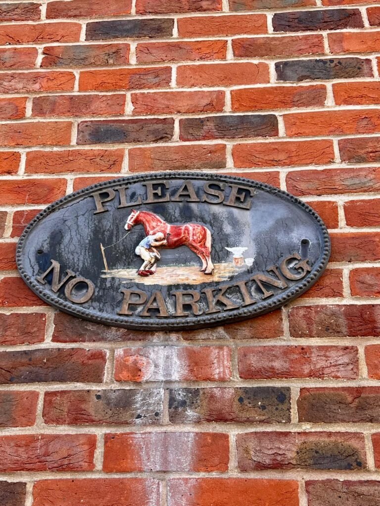 Decorative Please No Parking sign on a brick wall in Whitchurch