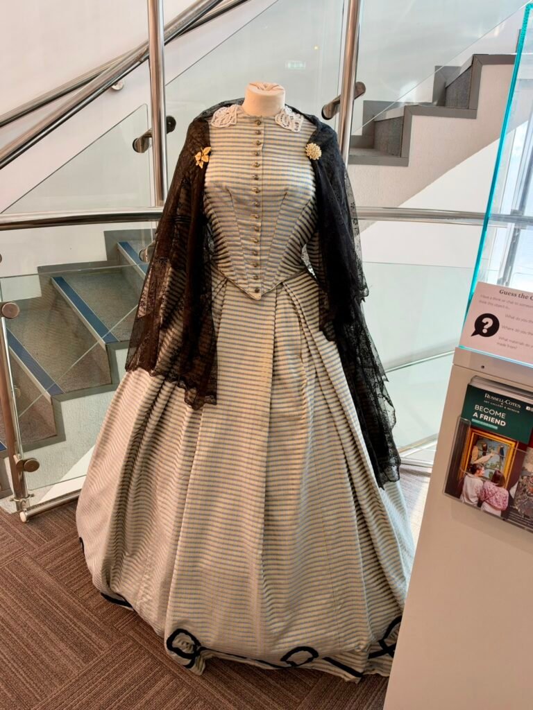 Modern recreation of Annie Russell-Cotes' striped wedding dress with black lace shawl from 1860