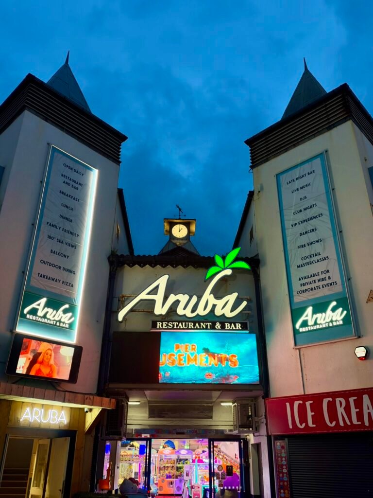 Illuminated Aruba Restaurant and Bar entrance with pier amusements at Bournemouth Pier