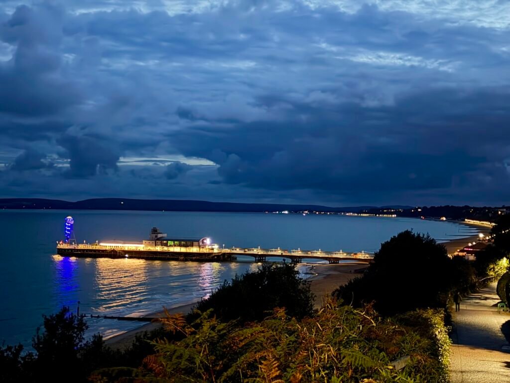 Bournemouth Pier glowing with golden and blue lights over the sea at night