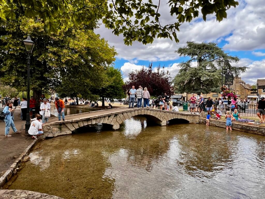 Visitors crowd a stone bridge over the River Windrush in Bourton-on-the-Water, Cotswolds.