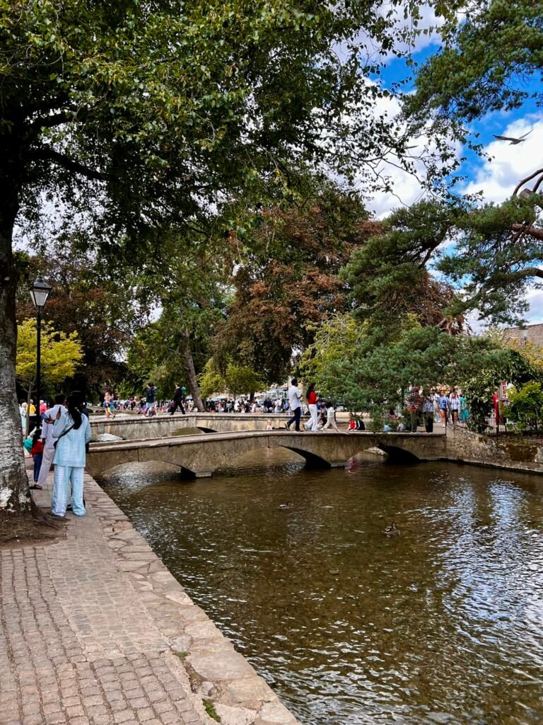 Riverside footpath, stone bridges, ducks and visitors along the River Windrush.