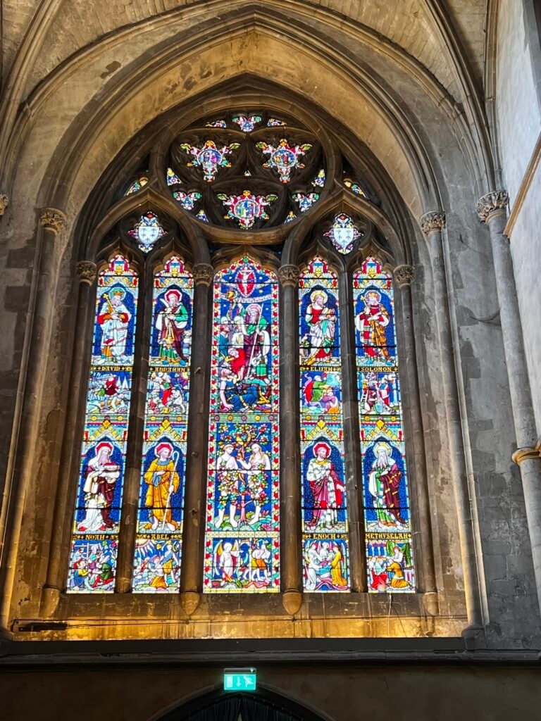 Colourful stained-glass window depicting biblical figures inside the Church of St Cross.