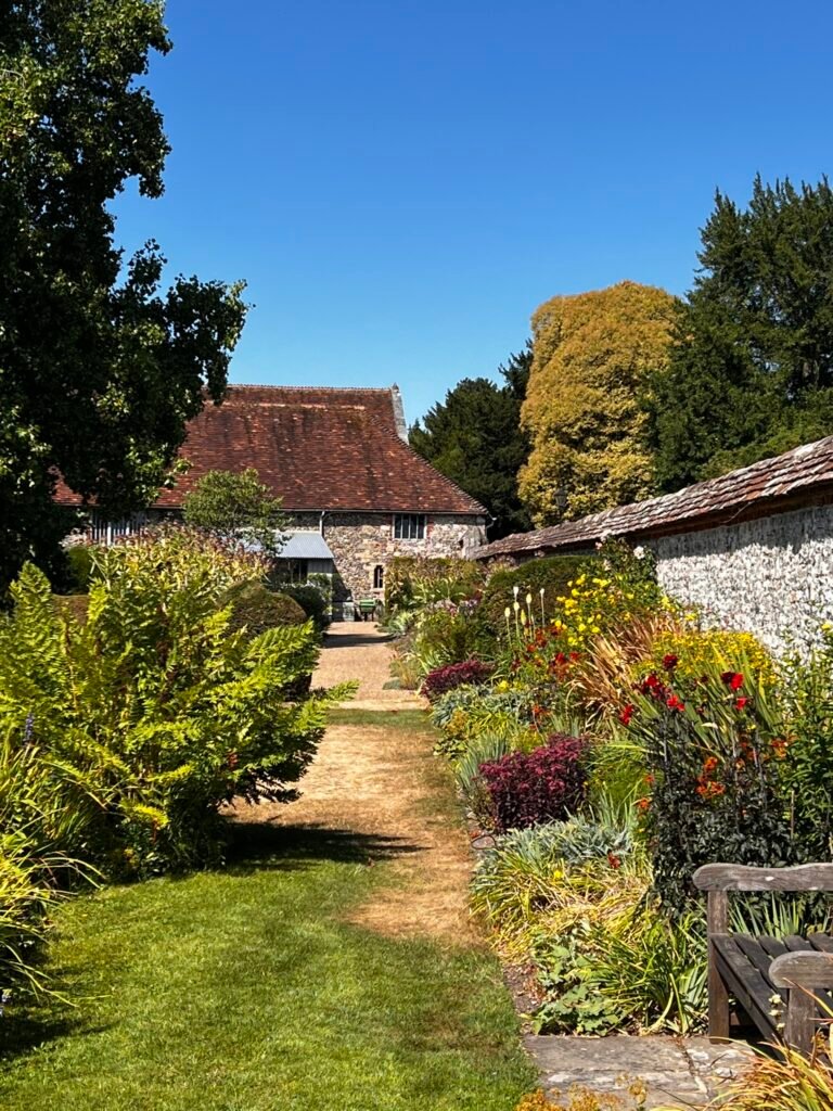 Flower-filled garden path between historic flint walls at the Hospital of St Cross.