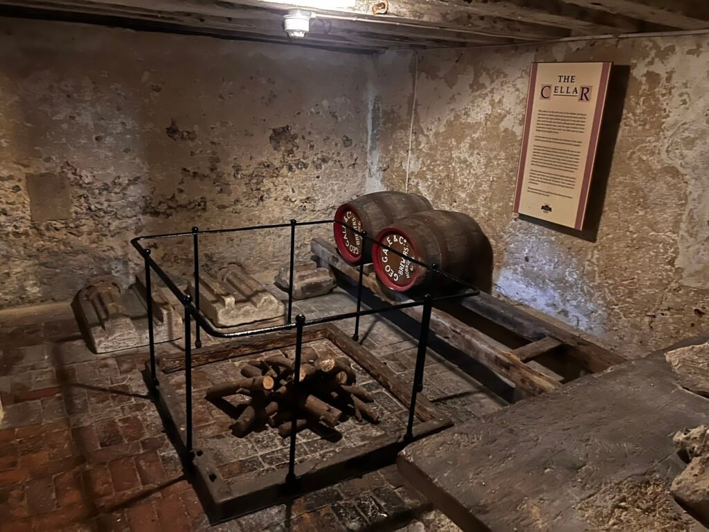Historic cellar with wooden barrels and storage equipment at the Hospital of St Cross.