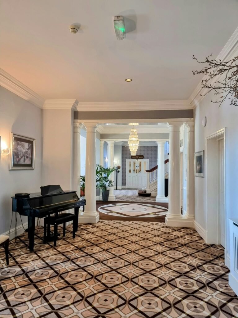 Black grand piano beside the library entrance at Hotel Miramar Bournemouth.
