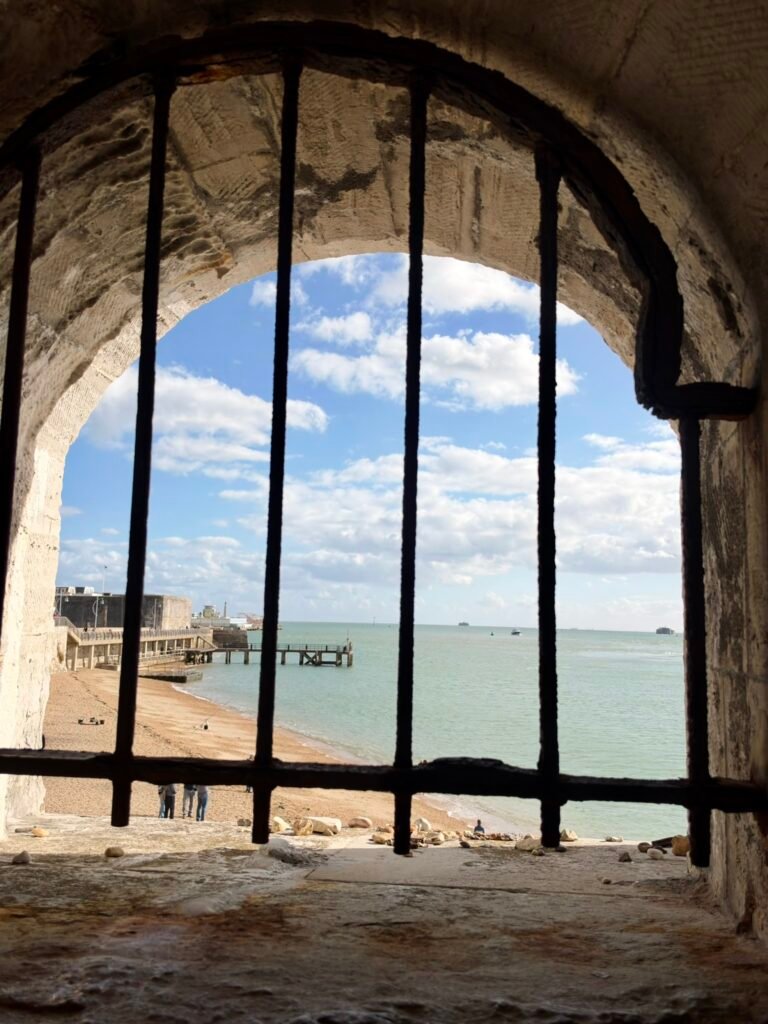 View of Portsmouth Harbour and beach through a barred stone window