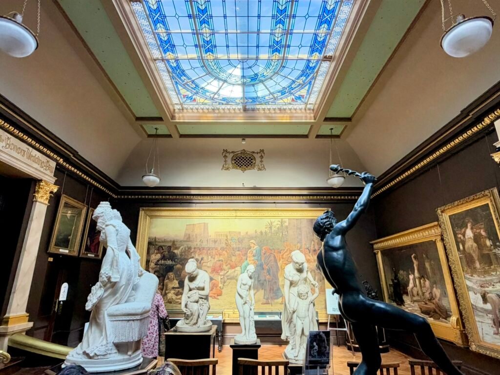 Marble statues and Edwin Long's Anno Domini beneath the blue gallery skylight at Russell-Cotes Museum