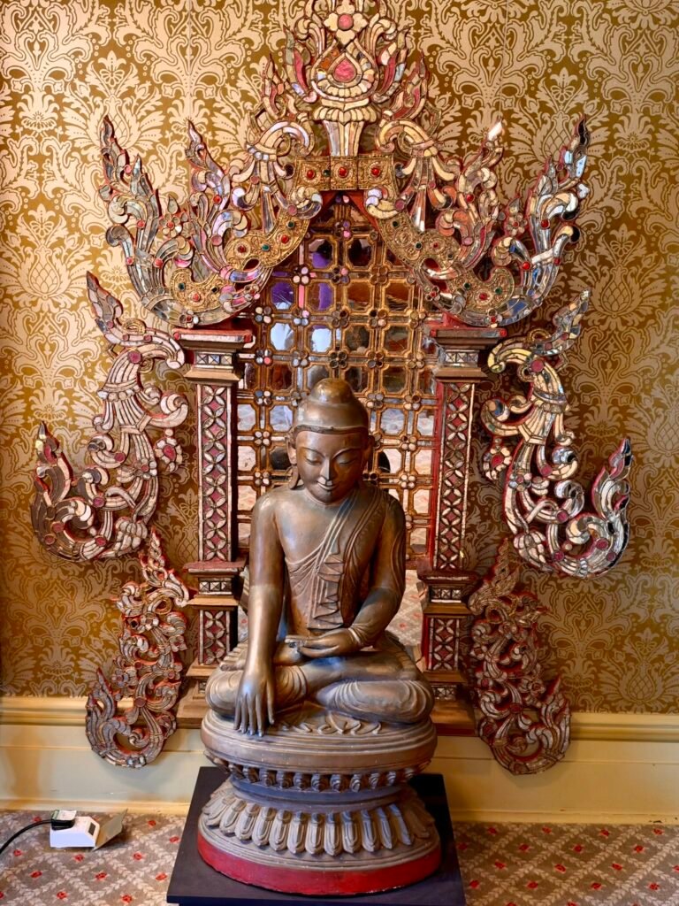 Seated Buddha sculpture framed by elaborate carved decoration in the Russell-Cotes Yellow Room