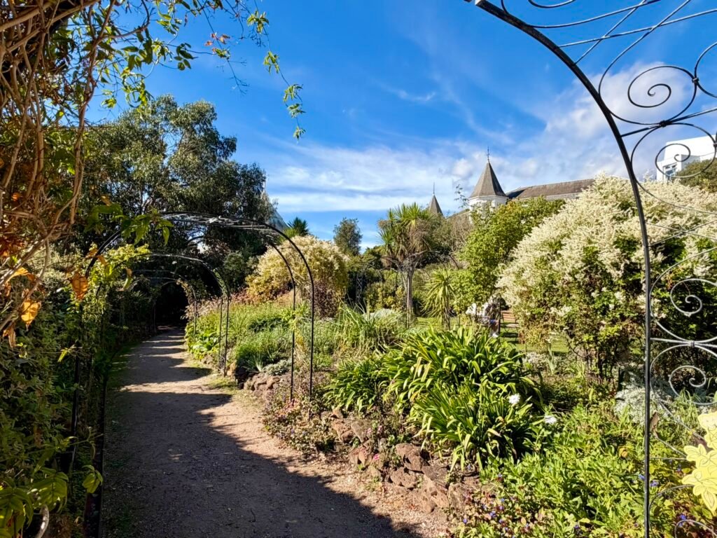 Gravel garden path running beneath curved iron plant arches at Russell-Cotes Museum in Bournemouth
