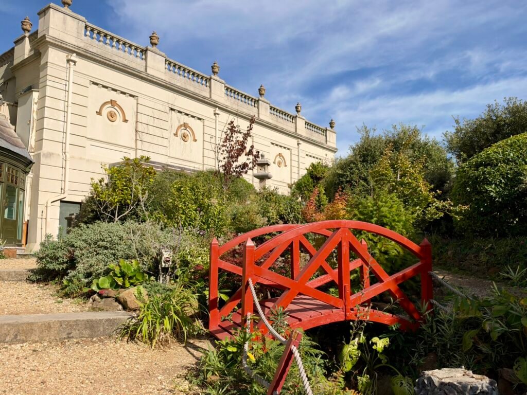 Small red wooden bridge among plants in the Japanese-inspired gardens at Russell-Cotes Museum