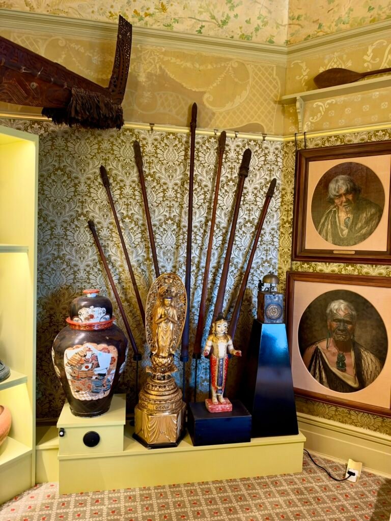 Portraits of Māori people, carved objects and ceremonial staffs in the Yellow Room at Russell-Cotes