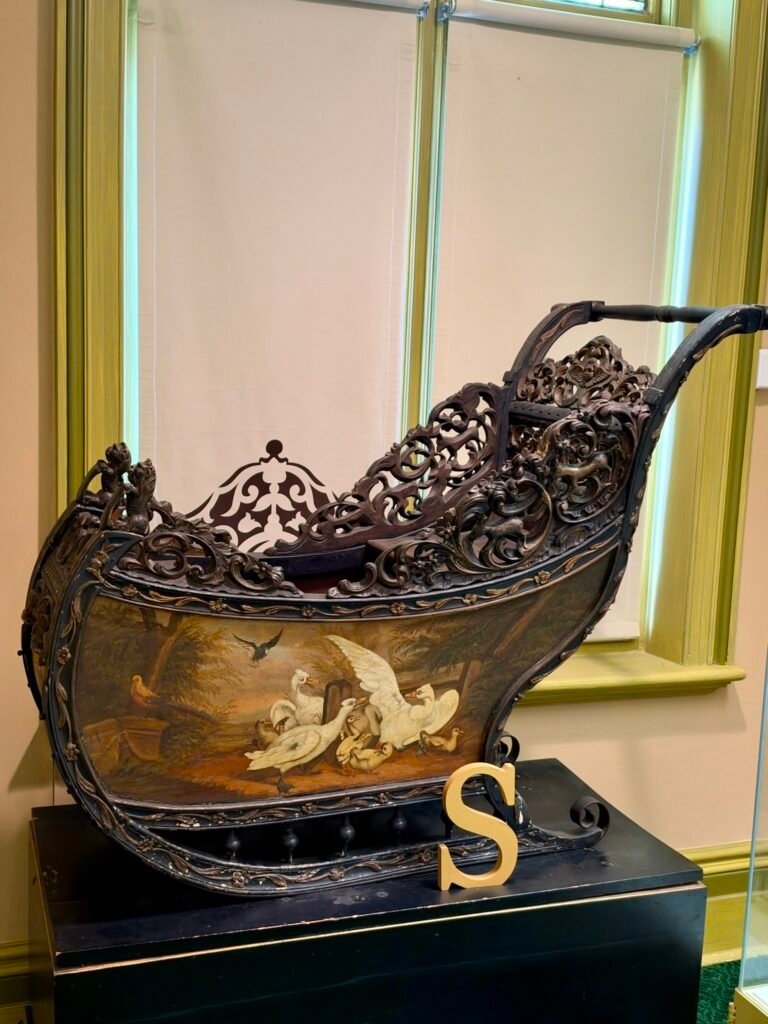 Ornate carved historical sleigh with painted waterbirds displayed at Russell-Cotes Museum in Bournemouth