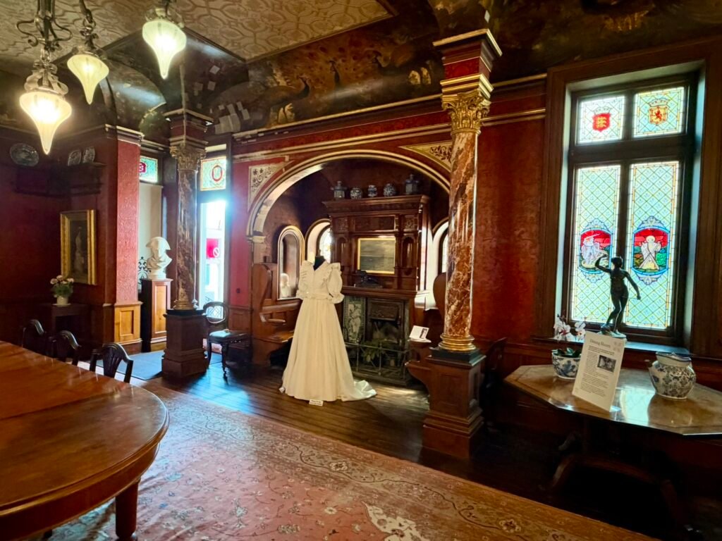 Wood-panelled Dining Room with stained-glass windows and painted peacock frieze at Russell-Cotes Museum