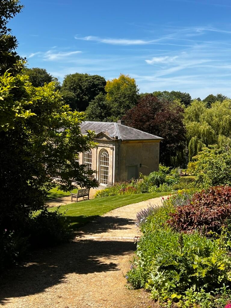 Gravel pathway descending through colourful gardens towards the Orangery