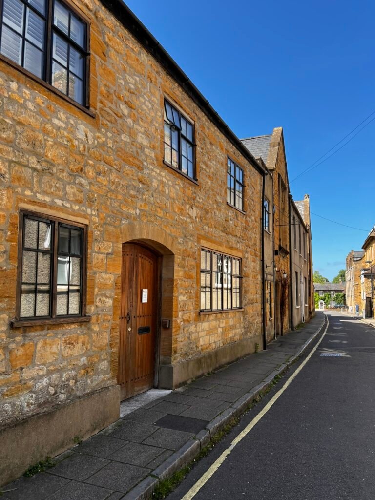 Quiet historic street in Sherborne lined with warm golden stone buildings