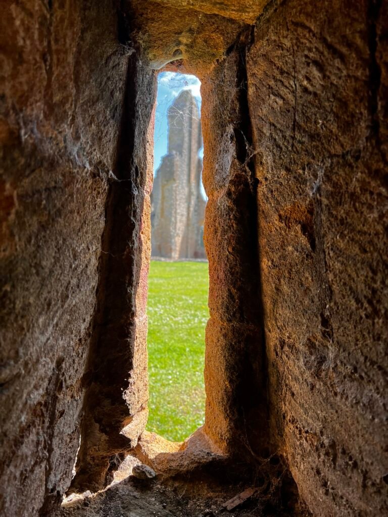 Narrow stone opening with cobwebs looking out across Sherborne Old Castle