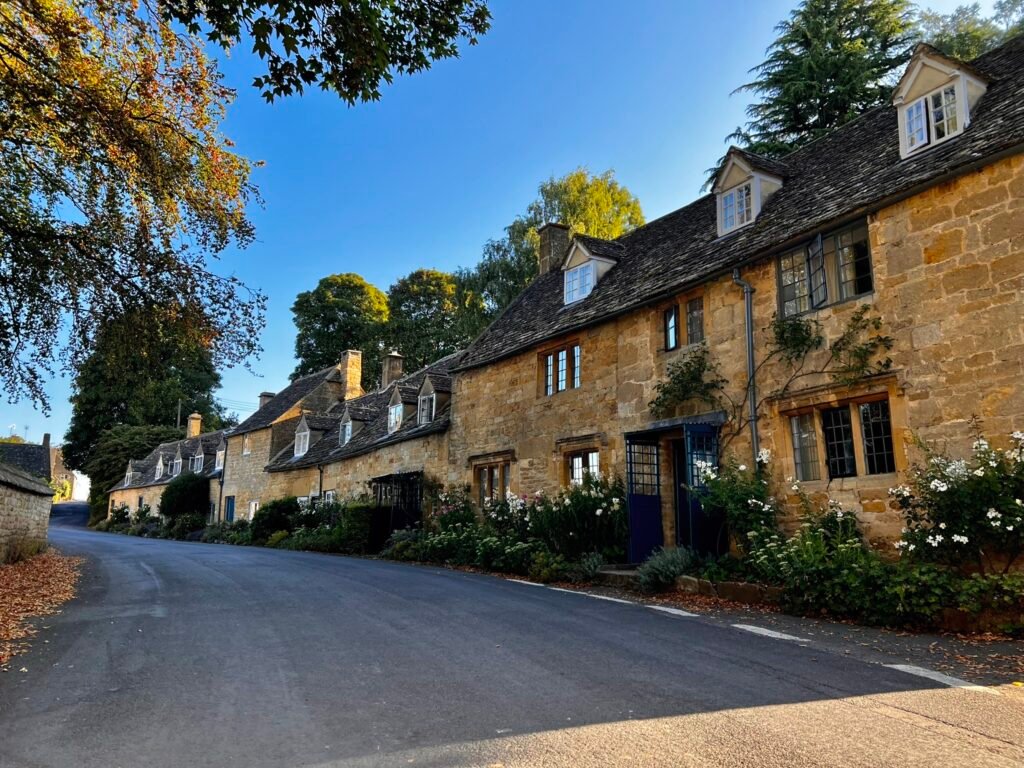 Golden Cotswold stone cottages lining a peaceful village lane in Snowshill, Gloucestershire.