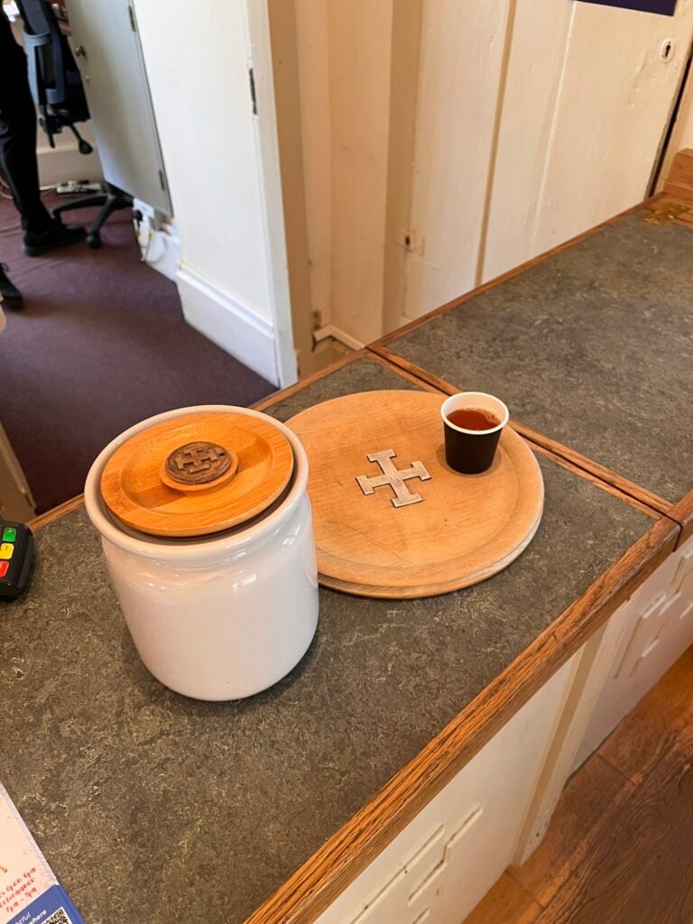Wooden serving tray, small cup of ale and lidded ceramic jar at St Cross.