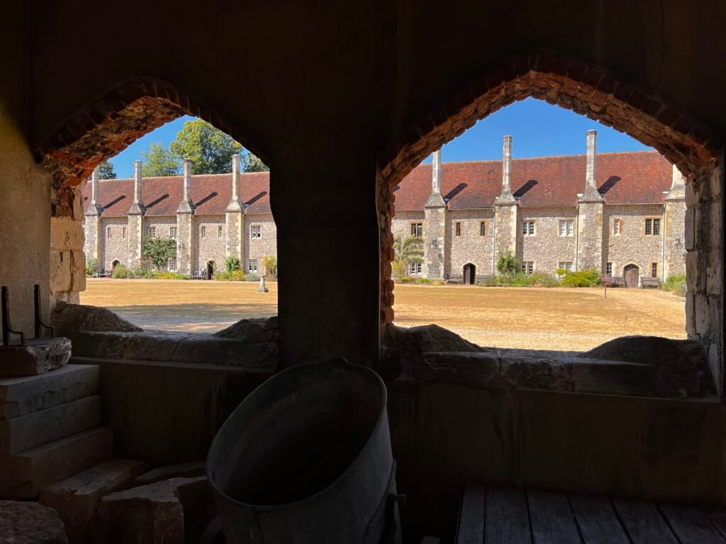 Almshouse homes for men who become a Brother at St Cross, Winchester, framed by two stone arches.