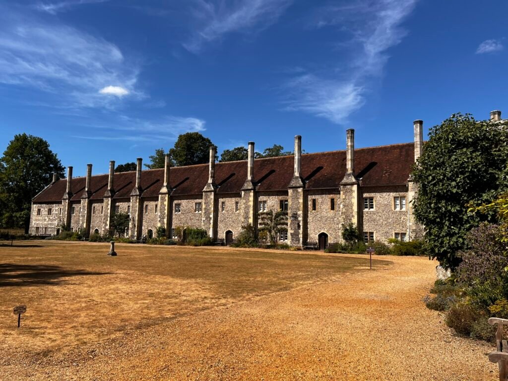 Long row of historic stone almshouses with tall chimneys at St Cross in Winchester.