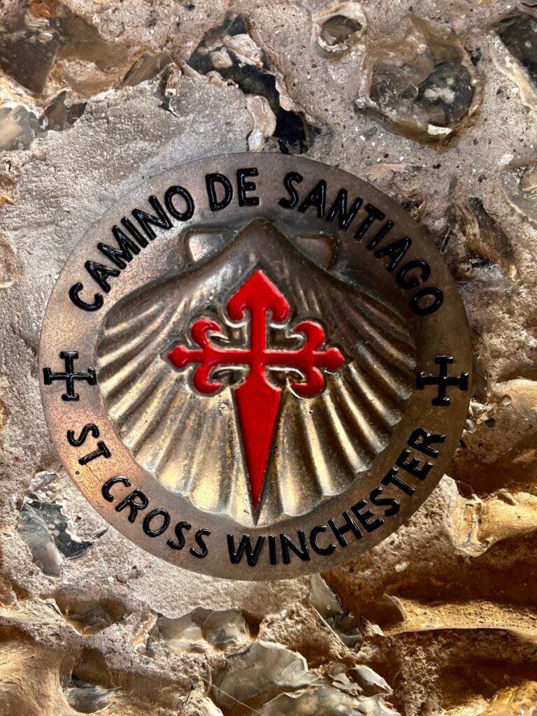 Camino de Santiago marker with a red cross and scallop shell at St Cross, Winchester.
