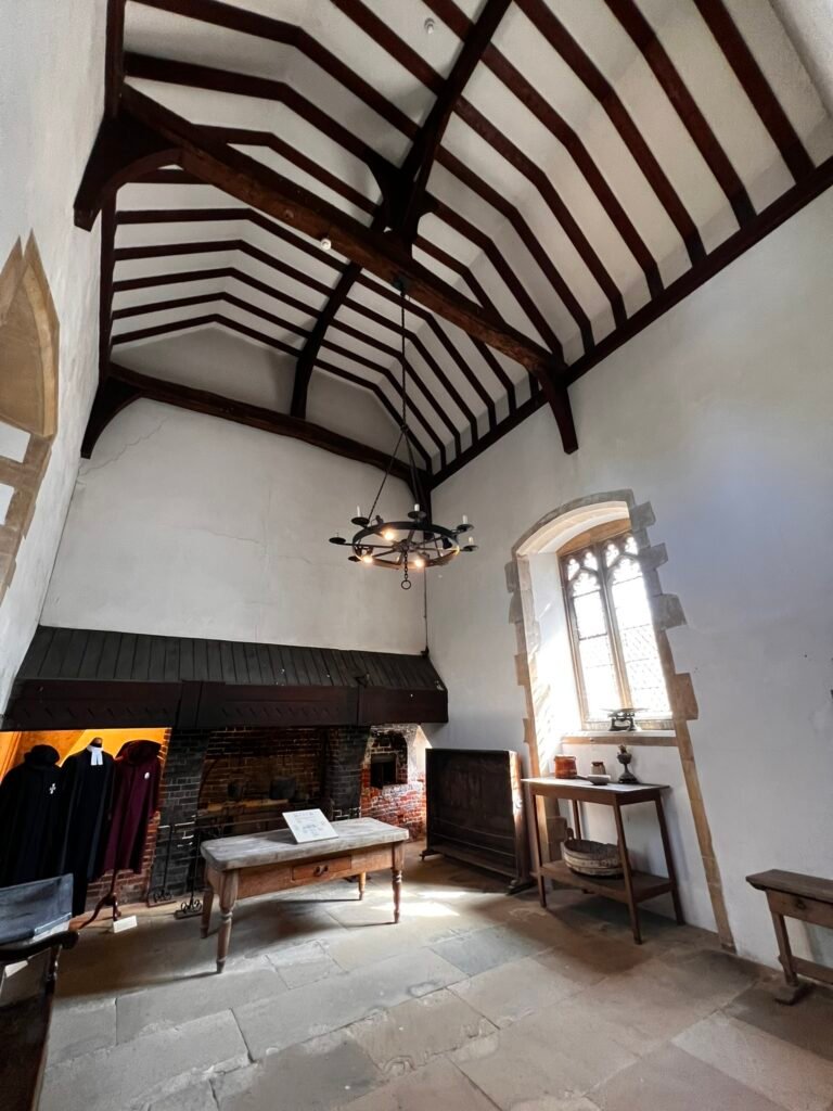 Historic St Cross kitchen with a large fireplace, wooden table and traditional robes