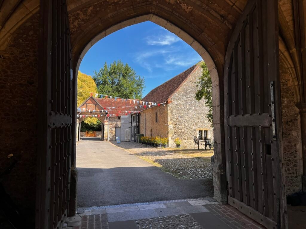 View through a medieval stone gateway towards the courtyard at St Cross, Winchester.