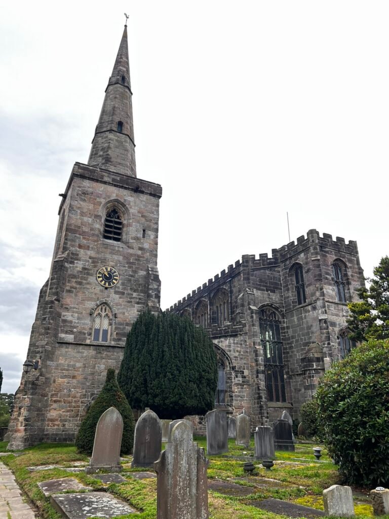 St Mary's Church in Astbury with its tall stone spire and old churchyard gravestones.