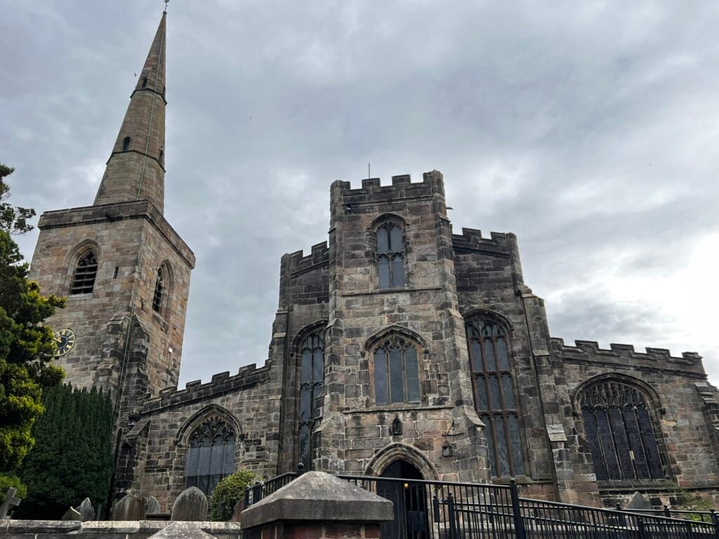 Gothic windows and battlemented stone walls at St Mary's Church in Astbury, Cheshire.